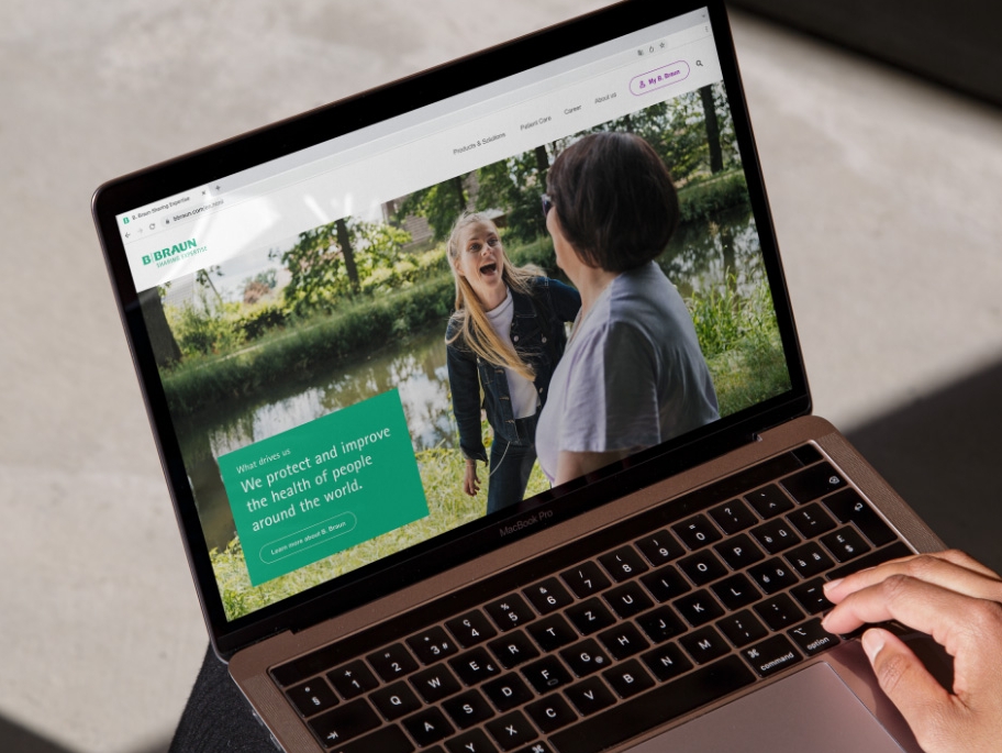 A laptop with the B. Braun website open and a hand resting on the bottom right of the laptop. 