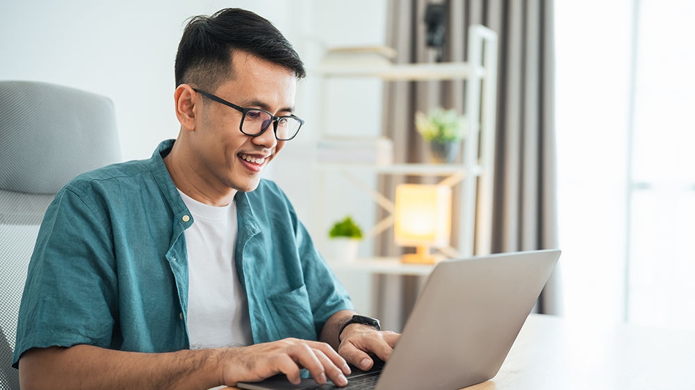 Smart Asian man smiling wearing glasses working with computer laptop. concept work form home, stay at home. freelance life style, New normal social distancing lifestyle. Work form anywhere concept.