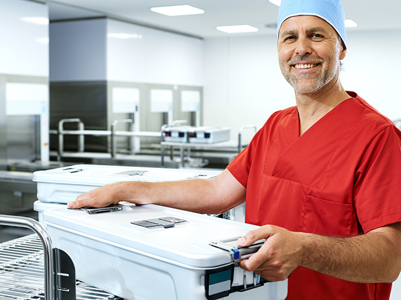 A male healthcare professional is holding a huge container smiling