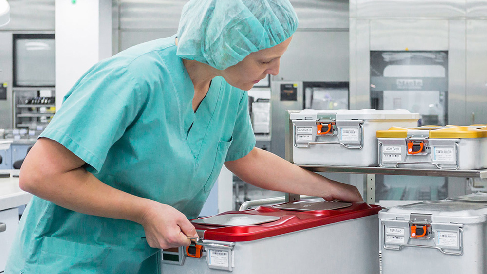 A female healthcare professional places a large container on a storage shelf in a medical supply room